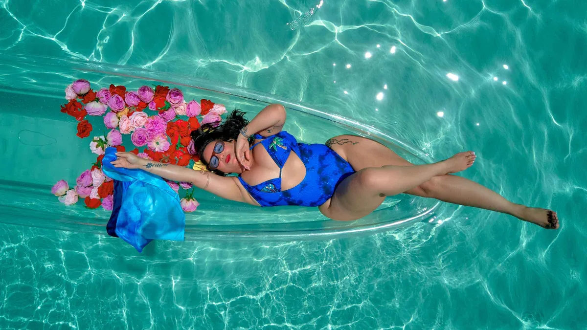 A woman posing in a floral-styled clear kayak on turquoise water during an Aruba glam photoshoot, Aruba