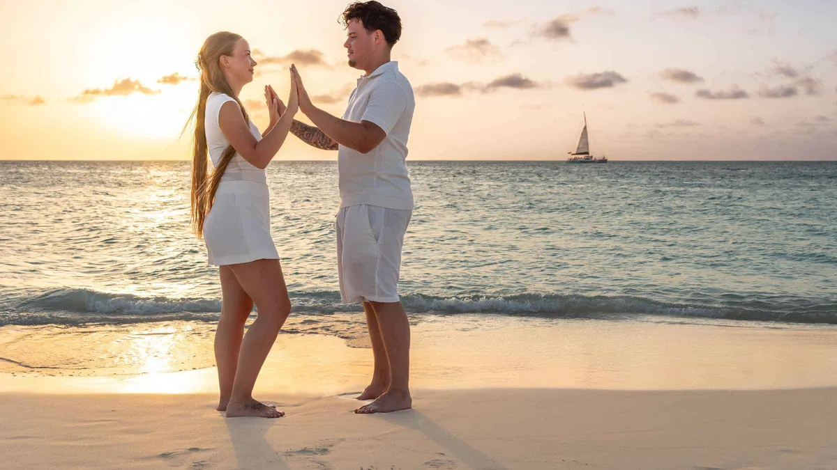 A couple walking hand in hand at the water's edge on Eagle Beach during a couples Aruba photoshoot at sunset, Aruba